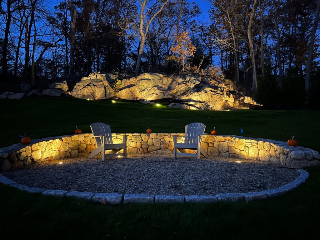 Landscape lighting highlights a backyard sitting area.