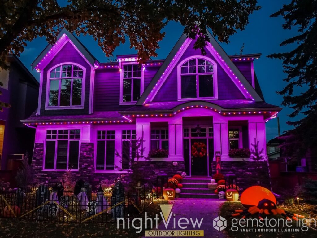 Permanent holiday lighting creates a vibrant purple glow and Halloween-inspired effects across the exterior of a home at night.